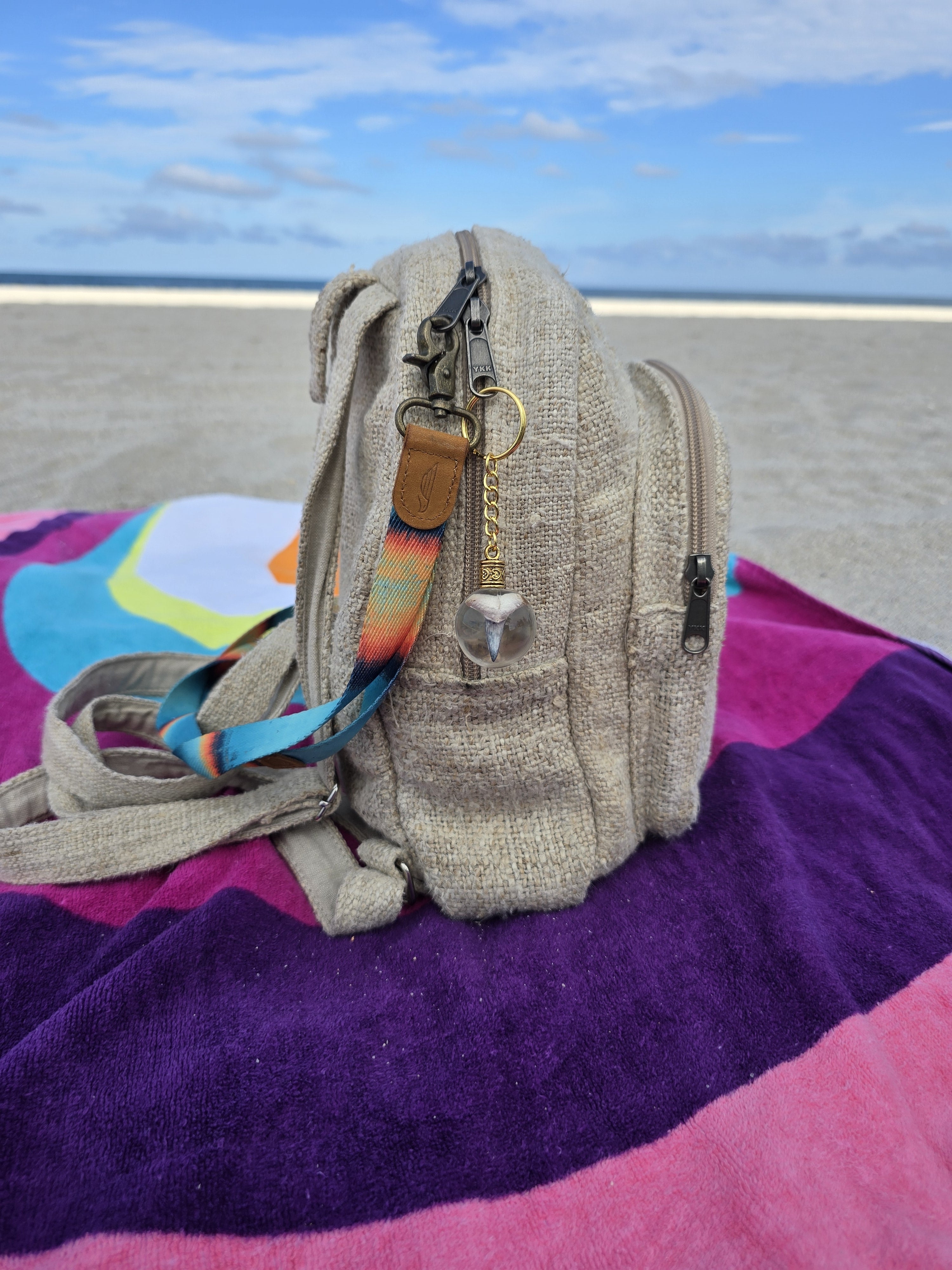 Bone Valley fossil mako shark tooth resin orb keychain clipped to a beach bag on a towel