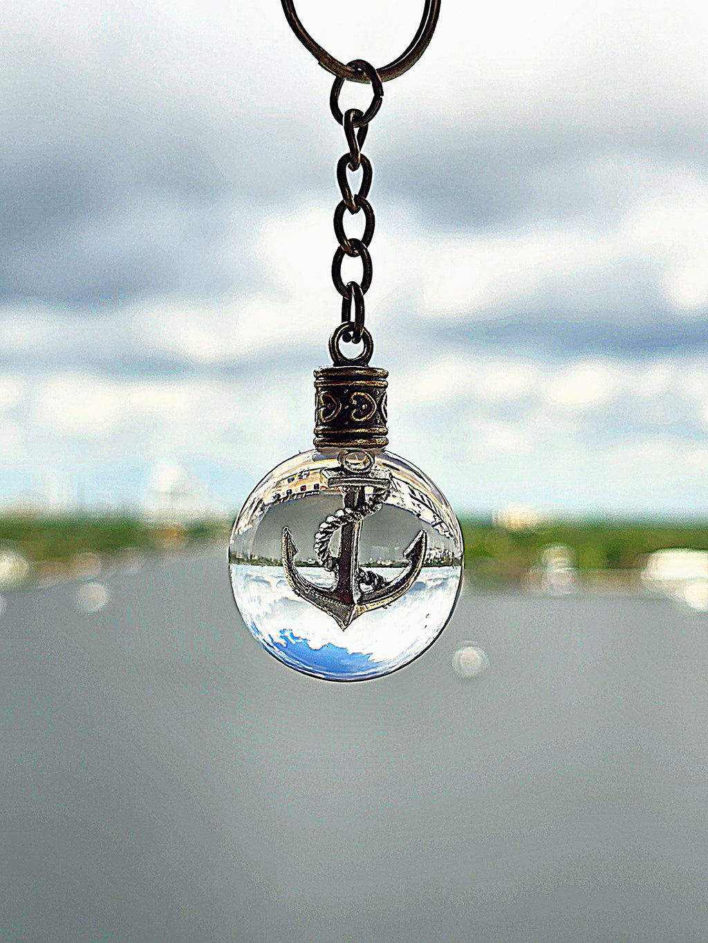 Anchor of Atlantis resin orb keychain against an intracoastal waterway
