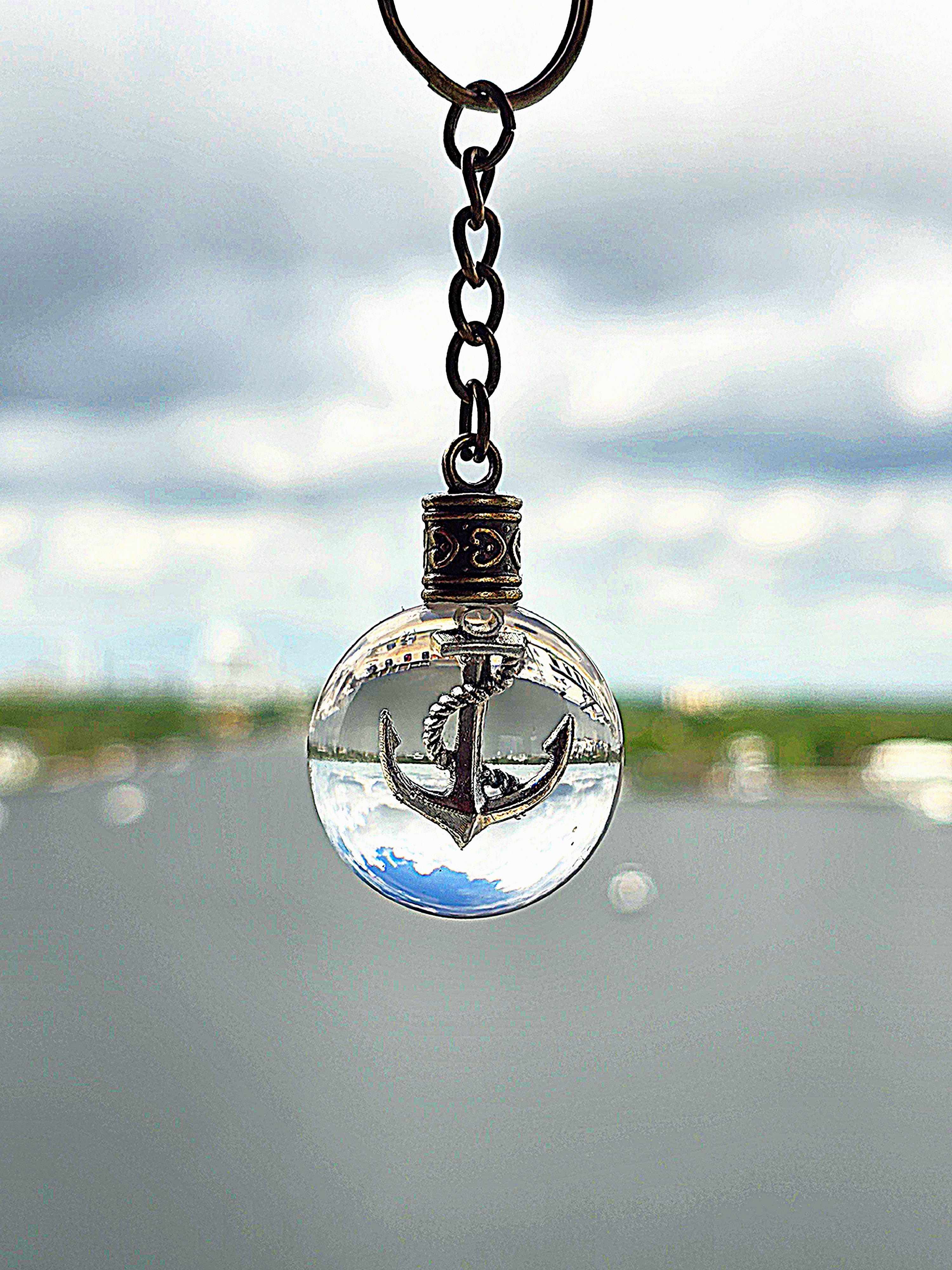 Anchor of Atlantis resin orb keychain against an intracoastal waterway