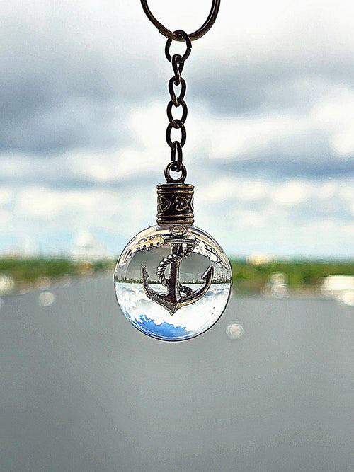 Anchor of Atlantis resin orb keychain against an intracoastal waterway