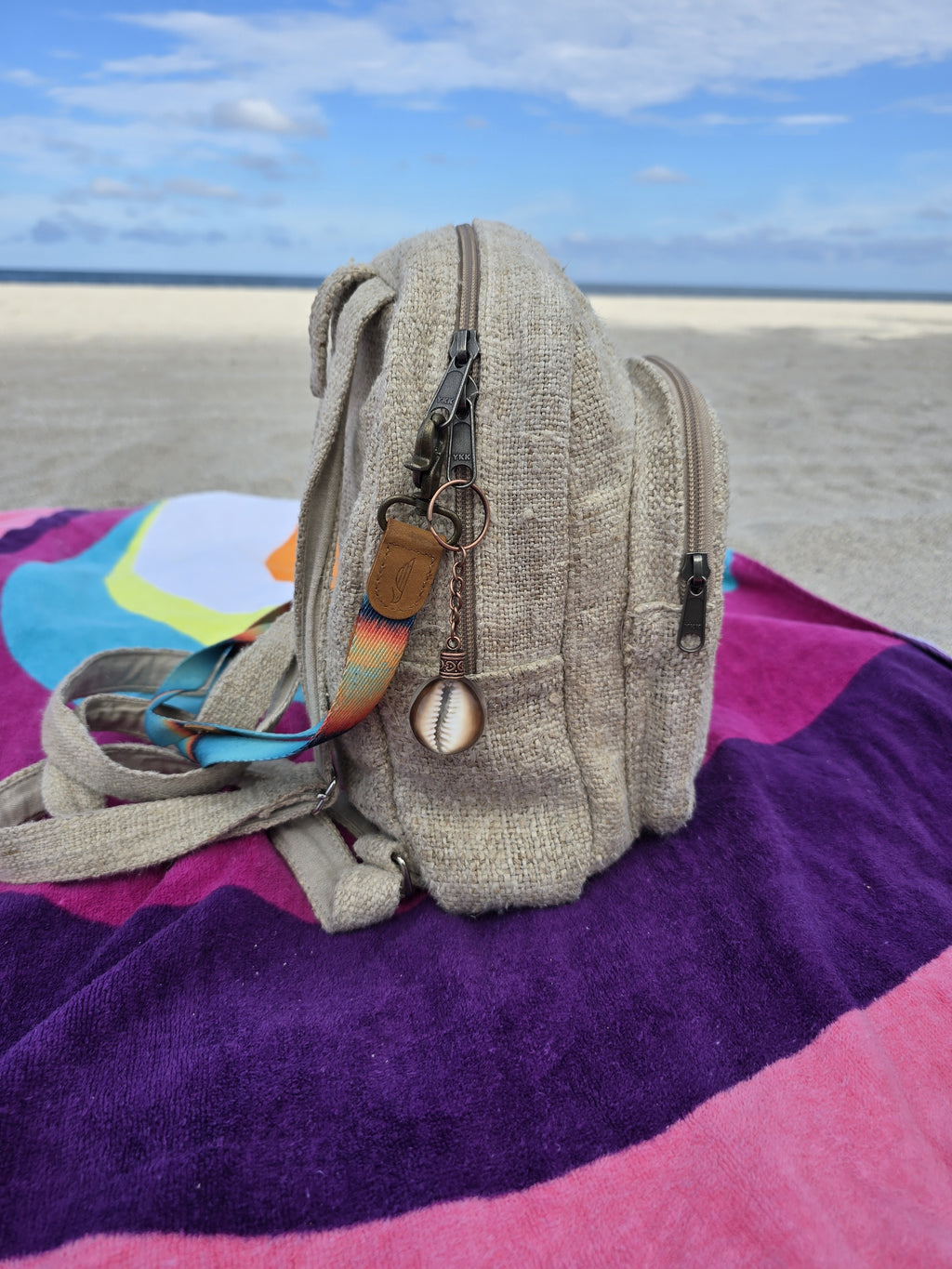 Brown cowrie shell resin orb keychain clipped to a beach backpack