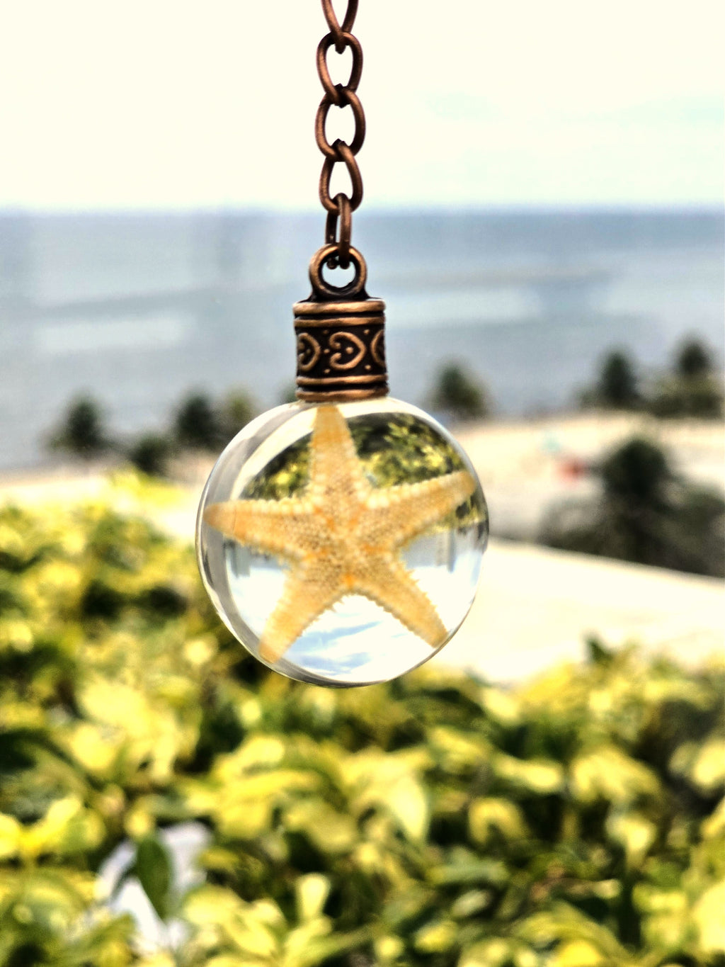 Sea Star of Atlantis resin orb keychain — beach and ocean backdrop