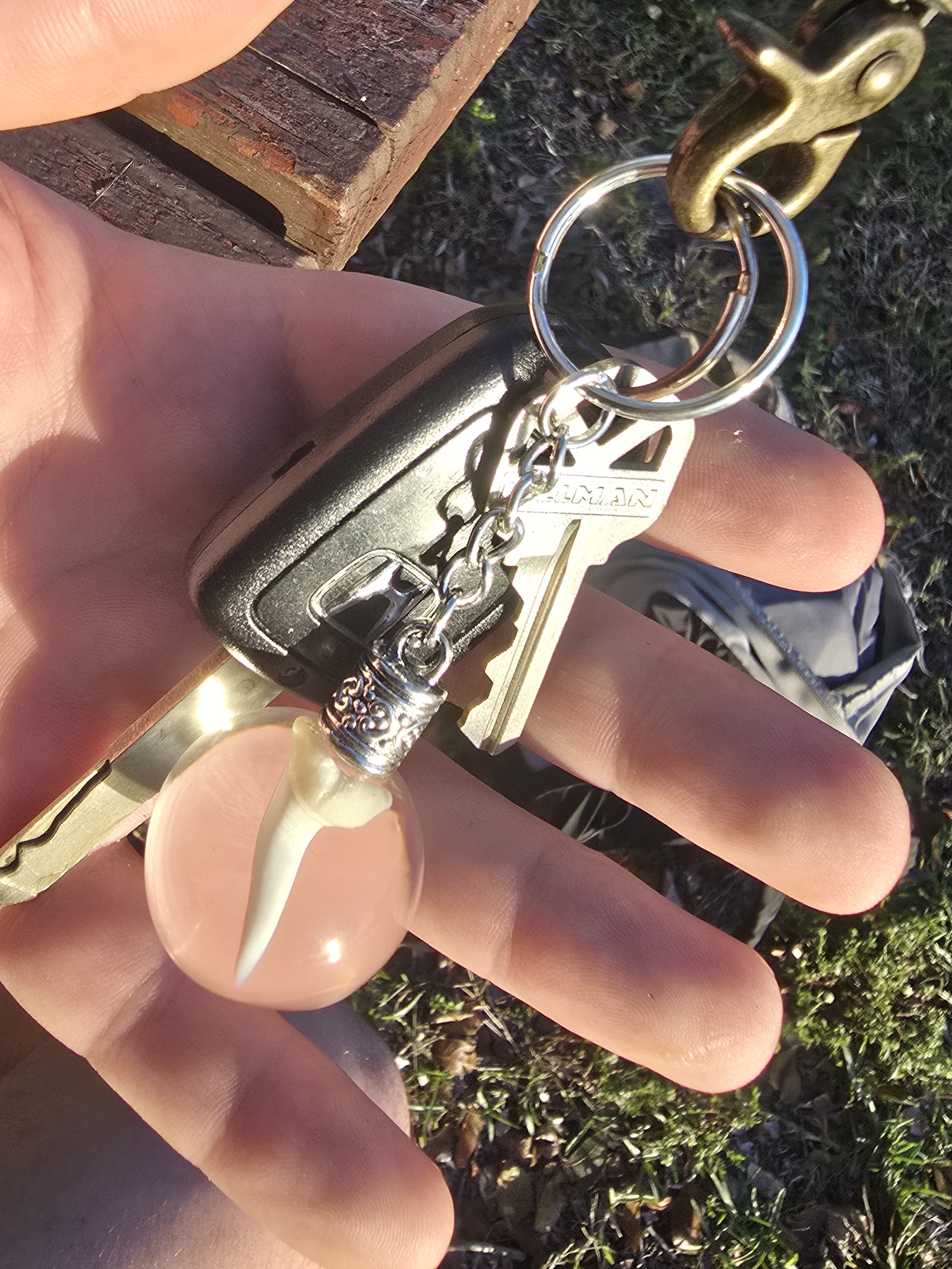 Mako shark tooth resin keychain attached to a set of car keys held in a hand outdoors